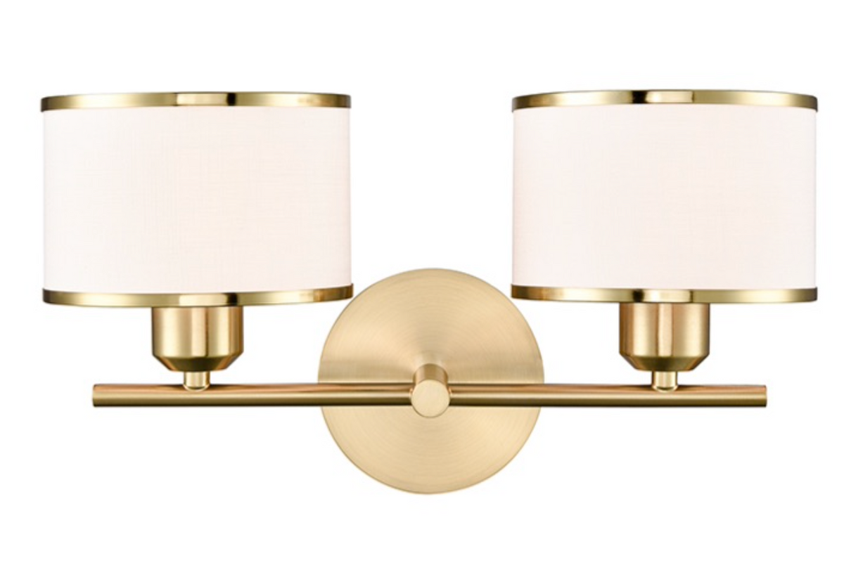A two-light wall sconce with a brushed gold metal frame and cylindrical white fabric shades, shown against a plain white background.